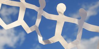 chain of paper people against a blue sky with white clouds