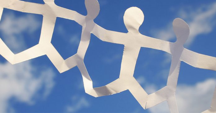 chain of paper people against a blue sky with white clouds