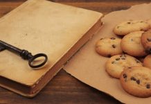 Photograph of a beige book with a black iorn key on it next to a piece of paper with cookies piled on it