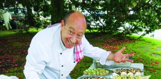 A photograph of chef Stephen Wilson leanind over a table laden with food