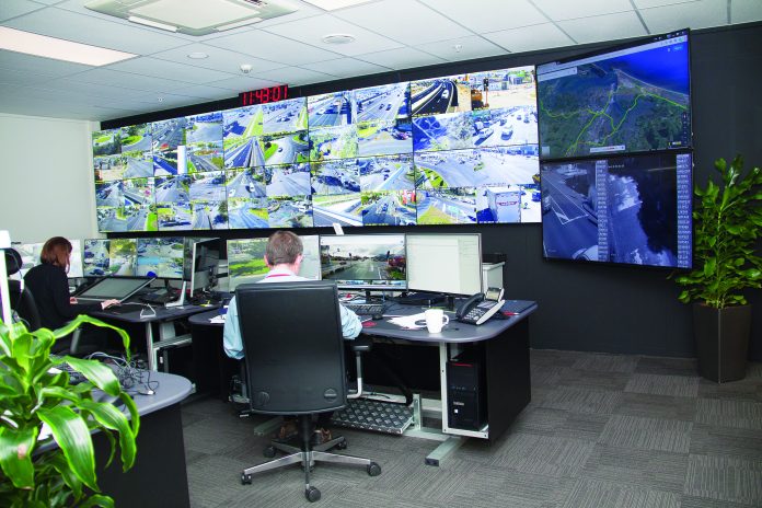 A picture of a man sitting in front of a bank of monitors at the Tauranga traffic control office