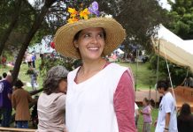 A woman in a white dress covered in pockets and wearing a straw hat carried a basket full of goodies