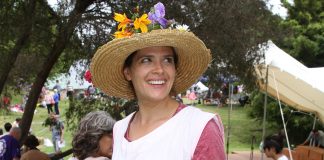 A woman in a white dress covered in pockets and wearing a straw hat carried a basket full of goodies