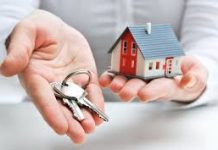 close up picture of investor holding a small house in one hand and a set of keys in their other hand