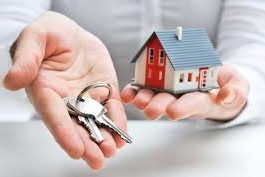 close up picture of investor holding a small house in one hand and a set of keys in their other hand
