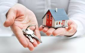 close up picture of investor holding a small house in one hand and a set of keys in their other hand
