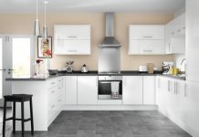 a picture of a showroom kitchen with white cupboards and a steel rangehood
