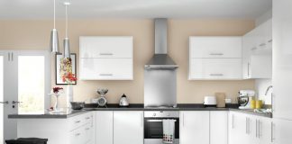 a picture of a showroom kitchen with white cupboards and a steel rangehood