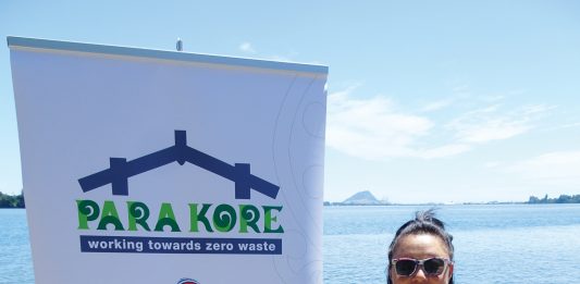 A maori woman standing next ot a sign for Para Kore Marae Incorporated Zero waste initiative