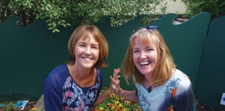 Photograph of two women sitting on a planter box at the Children's Garden preschool