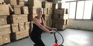 a woman sitting on an e-bike in a warehouse in front of cardboard boxes along one wall