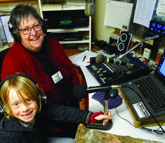 picture of a female DJ and a child in the broadcasting booth of the Historic Village Radio station