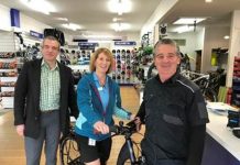 two men standing in a store next to a woman sitting on a bike