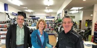 two men standing in a store next to a woman sitting on a bike