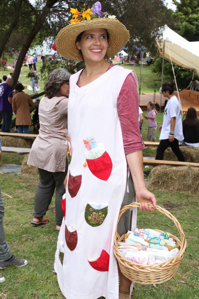 A woman in a white dress covered in pockets and wearing a straw hat carried a basket full of goodies