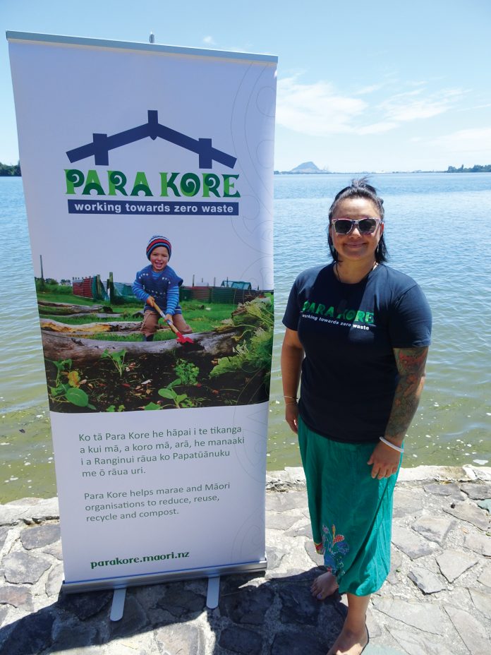 A maori woman standing next ot a sign for Para Kore Marae Incorporated Zero waste initiative