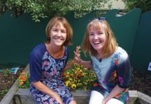 Photograph of two women sitting on a planter box at the Children's Garden preschool