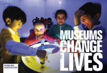 A group of children standing around a table with the caption Museums change lives