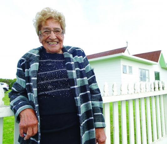photograph of Dene Reweti (92) standing in front of the all saints church
