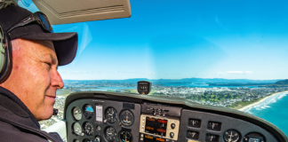 Paul Ensor at the controls of his plane flying over Tauranga coastline