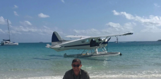 picture of a man on a beach with a seaplane behind him on the water
