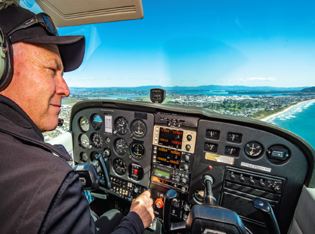 Paul Ensor at the controls of his plane flying over Tauranga coastline